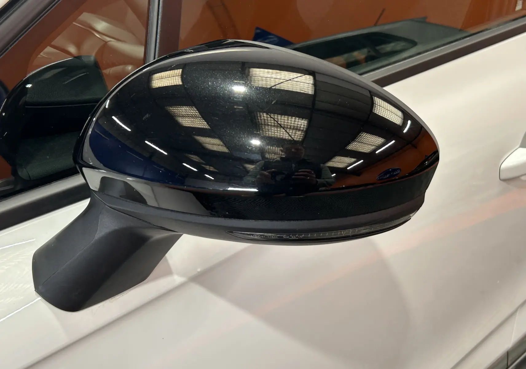 Rétroviseur extérieur noir côté gauche d’une Renault Clio V blanche, vue rapprochée sur la portière.