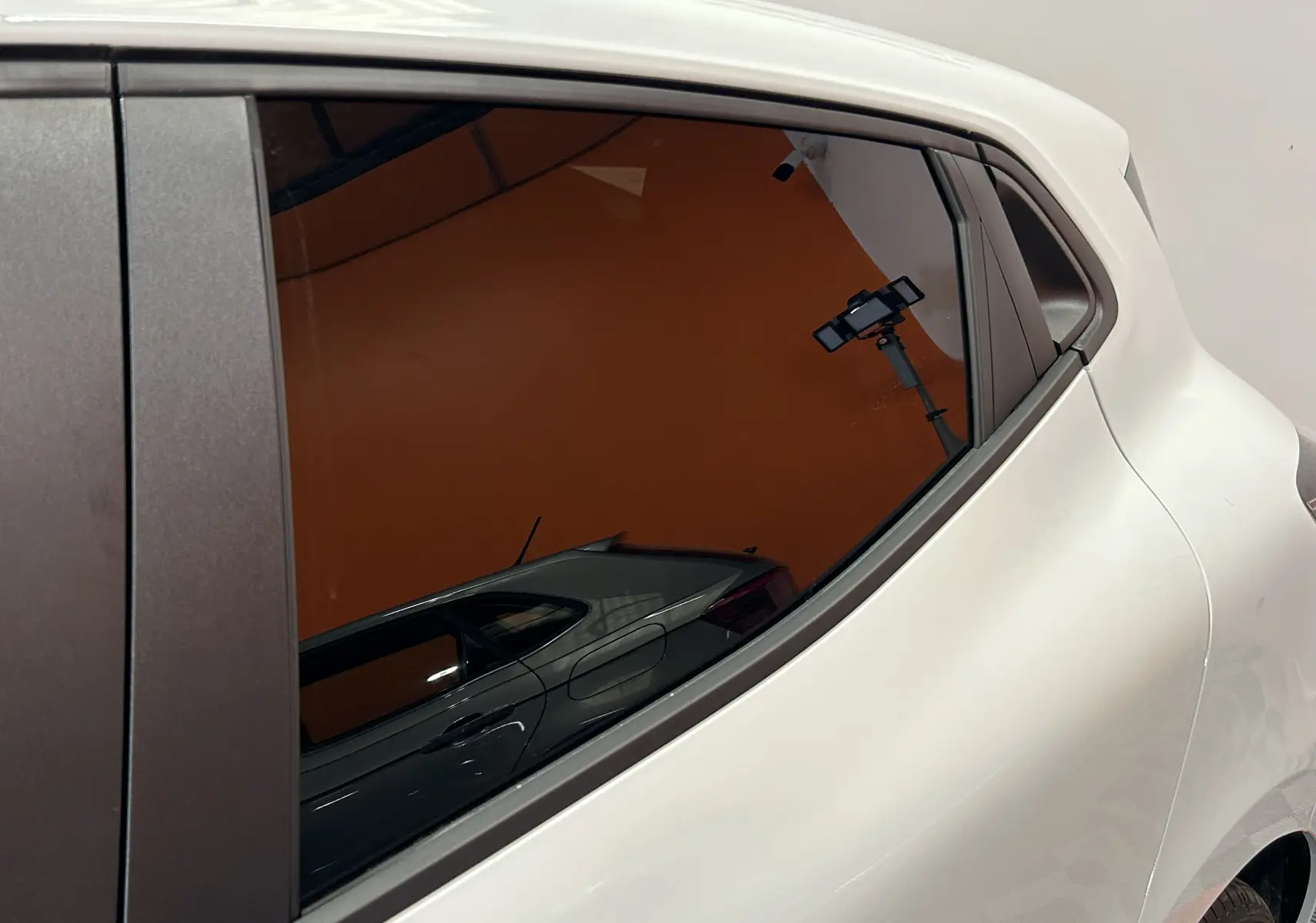 Gros plan sur la partie arrière droite blanche de la Renault Clio V, mettant en valeur la vitre latérale teintée et la poignée intégrée.