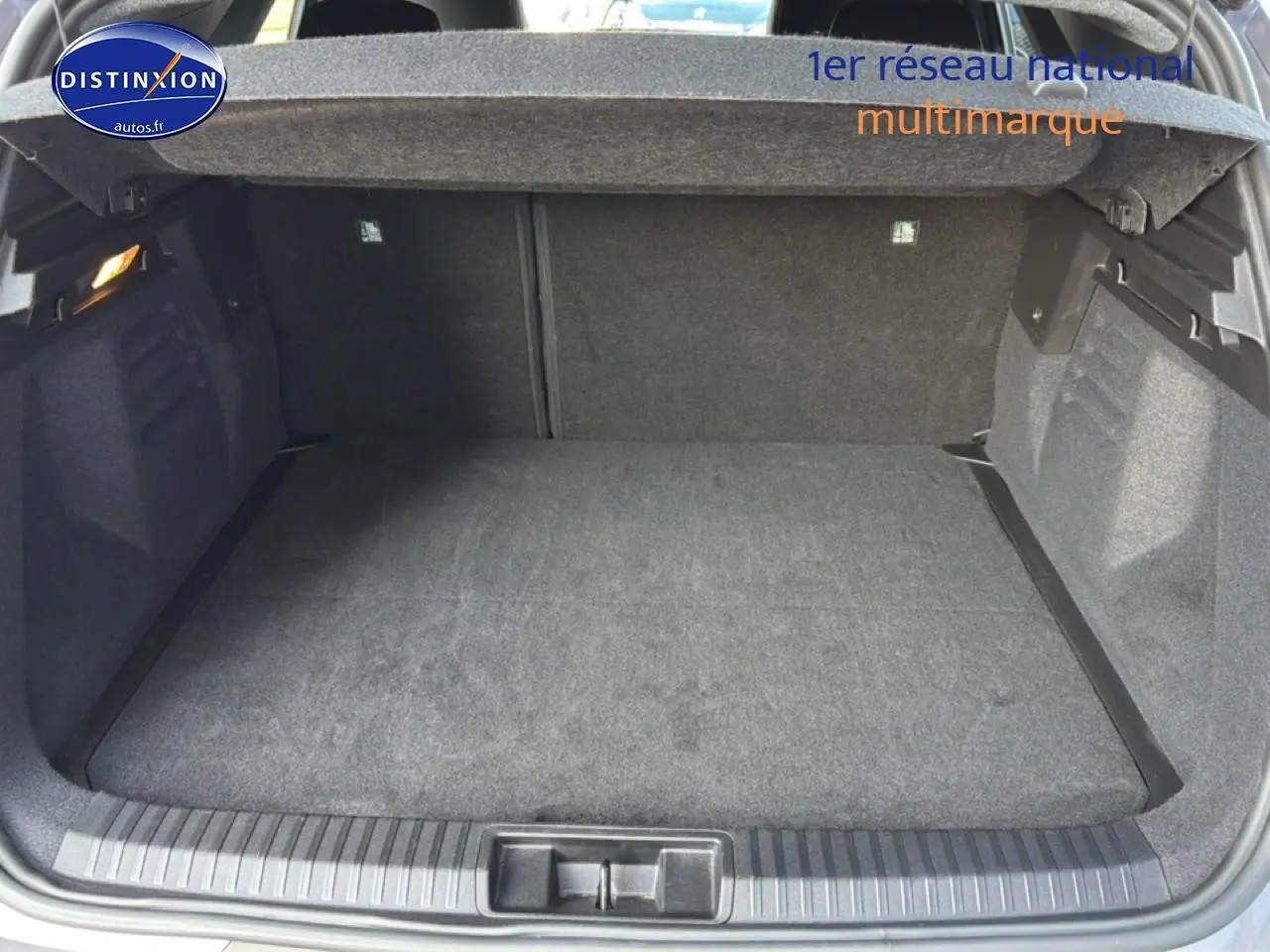 Coffre ouvert vu de l'arrière d'une Renault Symbioz 2025, intérieur de coffre gris avec tablette cache bagages.