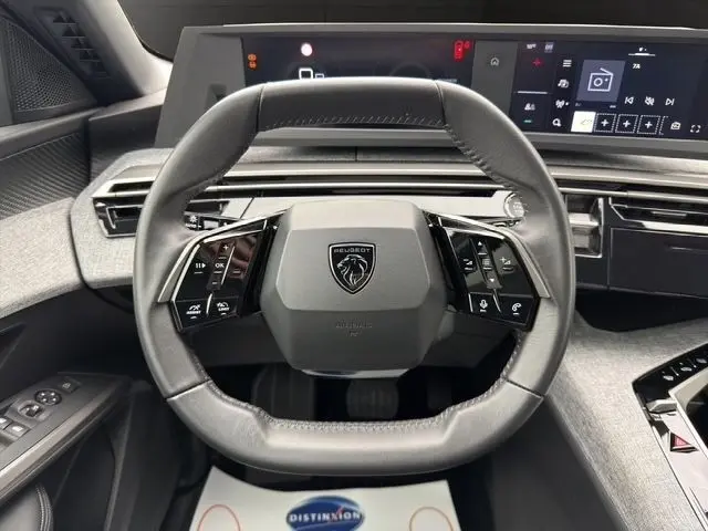 Vue rapprochée du volant cuir multifonctions du Peugeot 5008 blanc 2025 avec tableau de bord numérique et commandes intégrées.