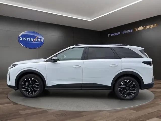 Vue de profil côté gauche d’un Peugeot 5008 blanc 2025 avec jantes noires et toit noir contrasté.