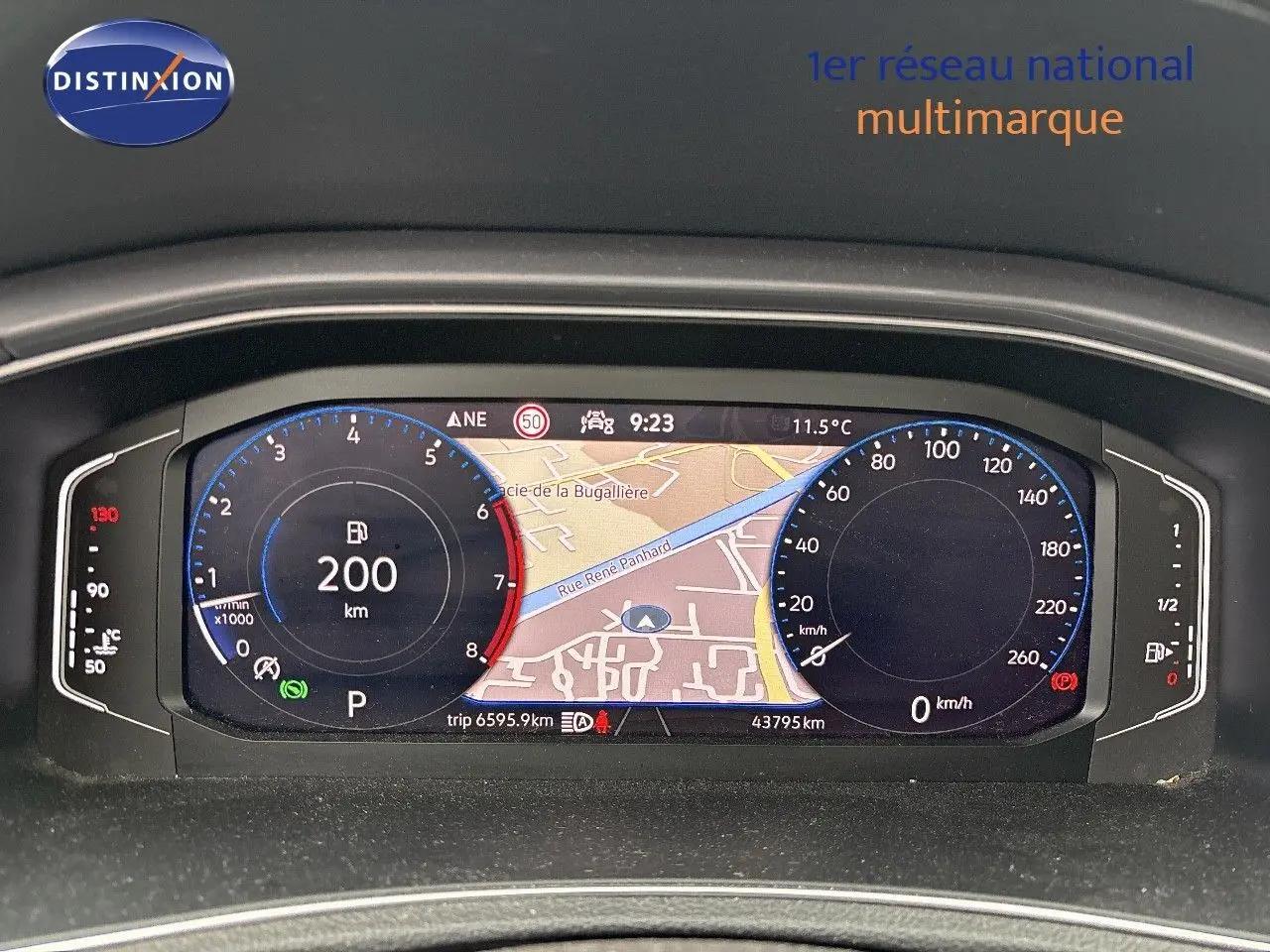 Tableau de bord numérique du Volkswagen T-Roc blanc argenté, affichant la navigation et compteurs à 9h23, intérieur moderne.