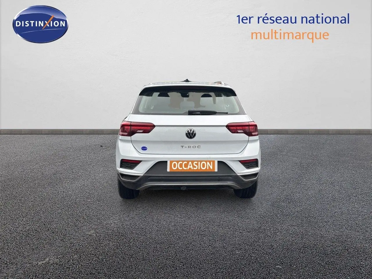 Vue arrière d'un Volkswagen T-Roc blanc argenté 2021 avec plaque orange "OCCASION" sur un sol gris.