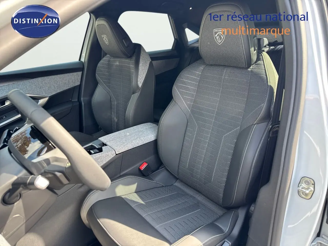 Vue intérieure côté conducteur du Peugeot 3008 blanc Okenite 2025, sièges en tissu et cuir noir avec logo GT brodé.