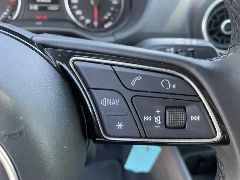 Gros plan sur les commandes gauche du volant noir de l'Audi Q2 2022, avec boutons de navigation et téléphone.