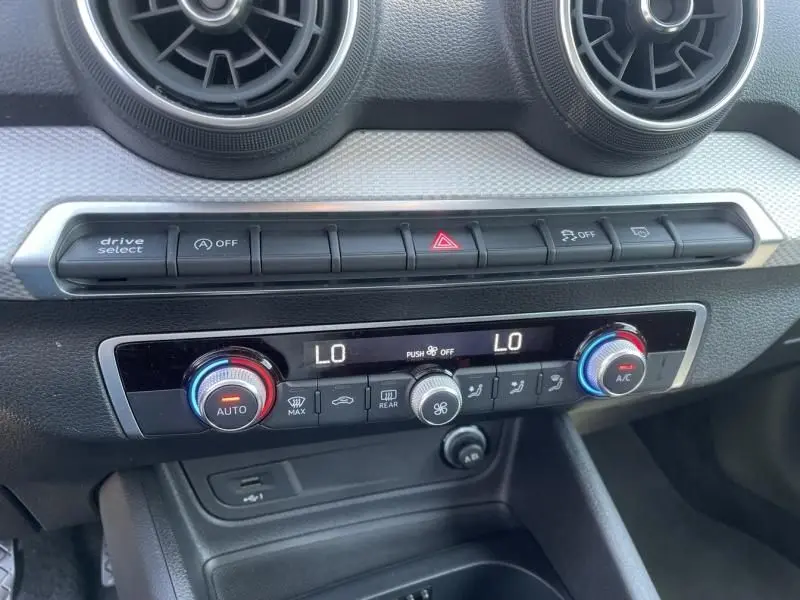 Détail du tableau de bord et climatisation automatique de l'Audi Q2 noir métal, 2022, avec commandes digitales et aérateurs ronds.