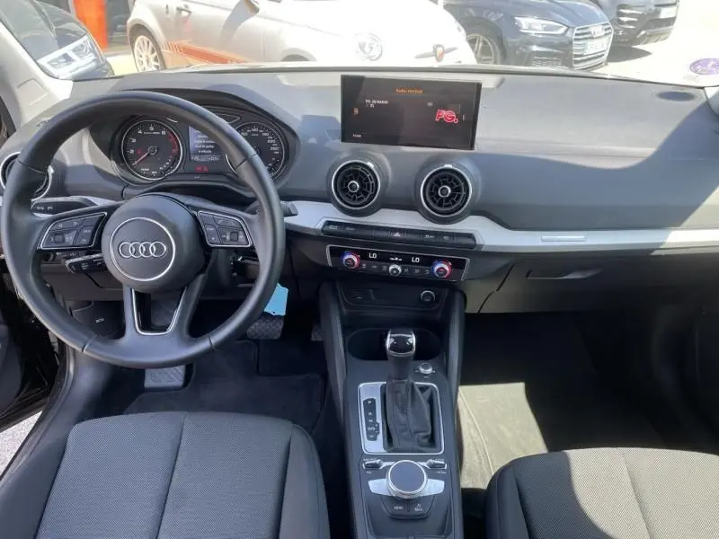 Intérieur de l'Audi Q2 TFSI 150CV 2022 en noir métal, vue de face sur le tableau de bord et la console centrale.