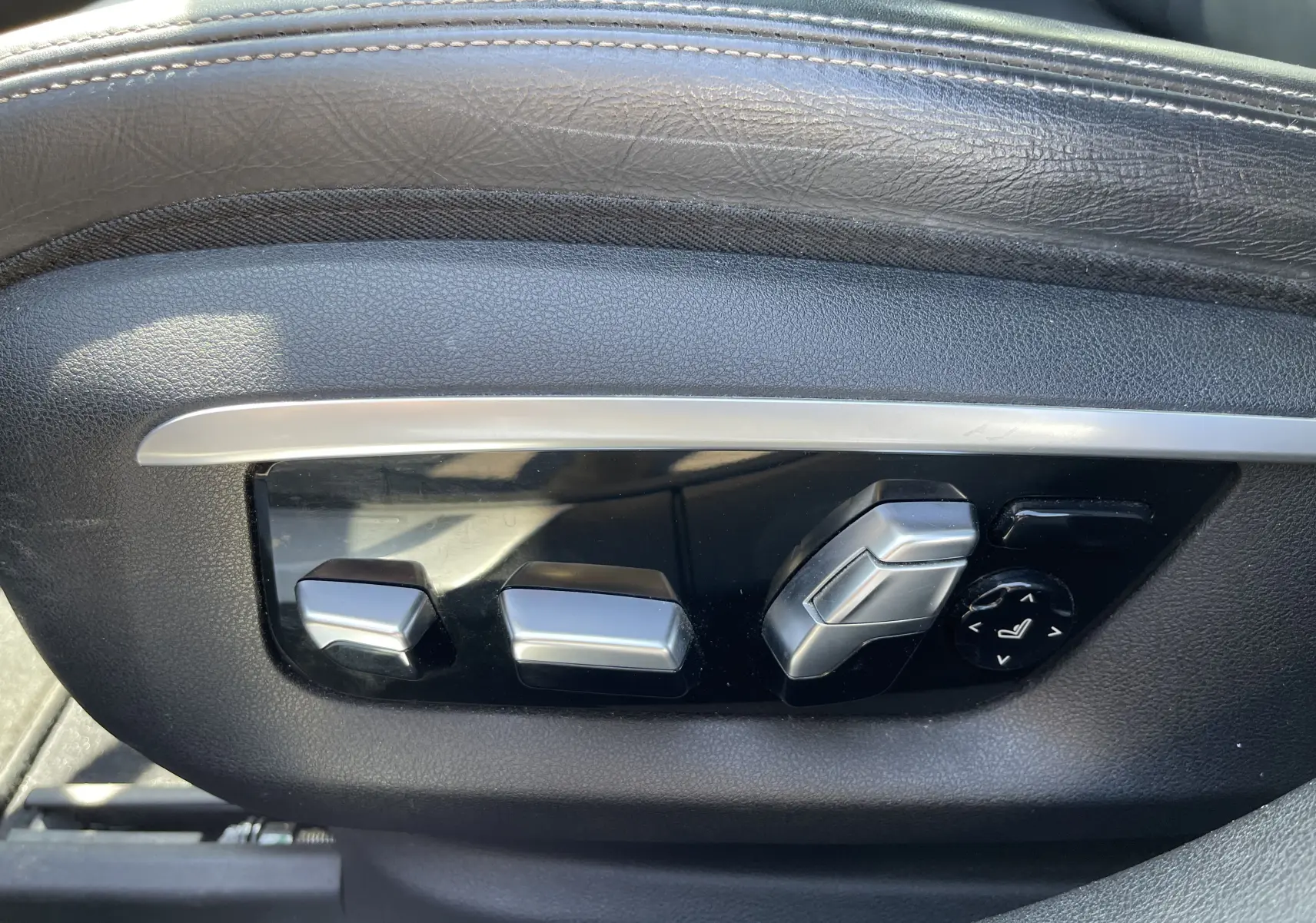 Gros plan sur les commandes électriques de réglage du siège en cuir noir d'une BMW Série 7 G11 730 XDA M Sport 2015.