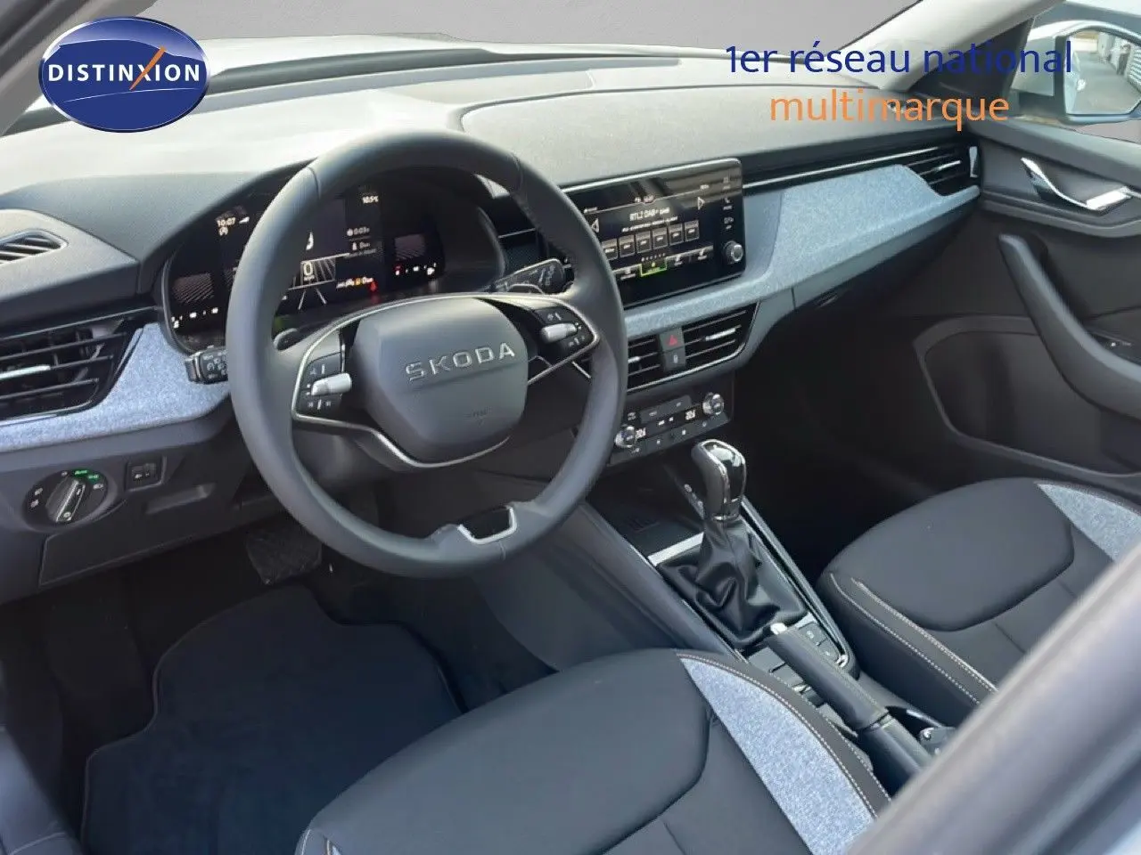 Intérieur de la Skoda Kamiq gris argent, vue côté conducteur montrant le tableau de bord et la console centrale moderne.