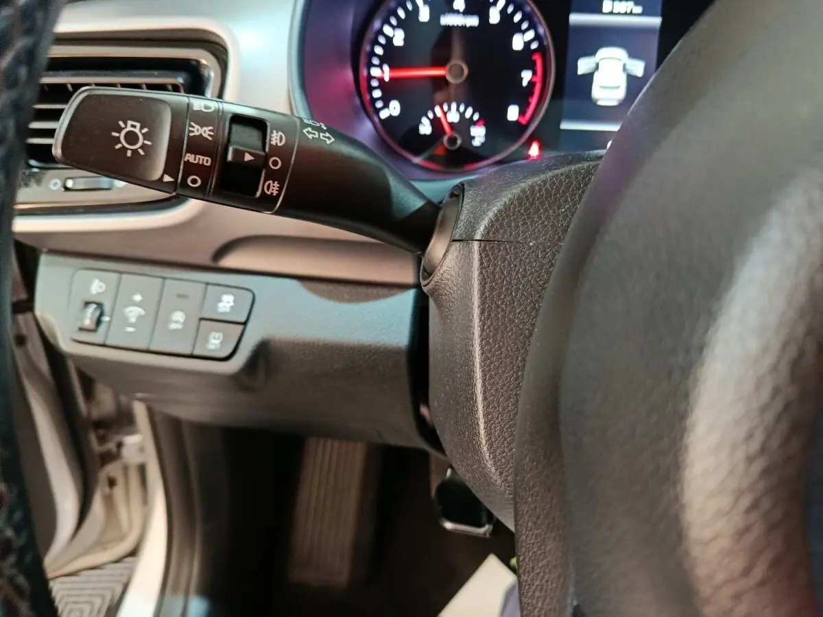 Gros plan sur le commodo d’éclairage et le tableau de bord numérique de la KIA Stonic gris clair, version 2022.