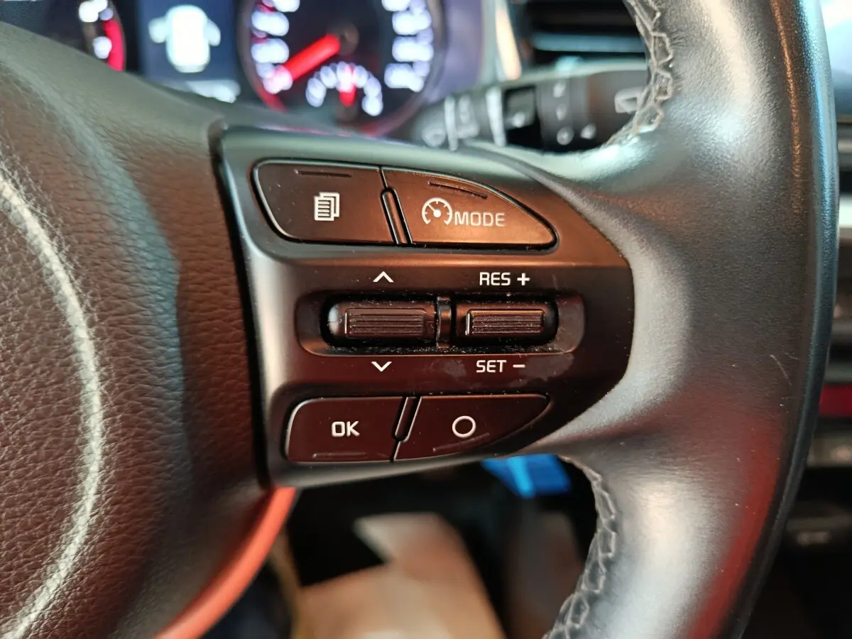 Gros plan sur les commandes de régulateur de vitesse au volant noir du KIA STONIC gris clair, version 2022.