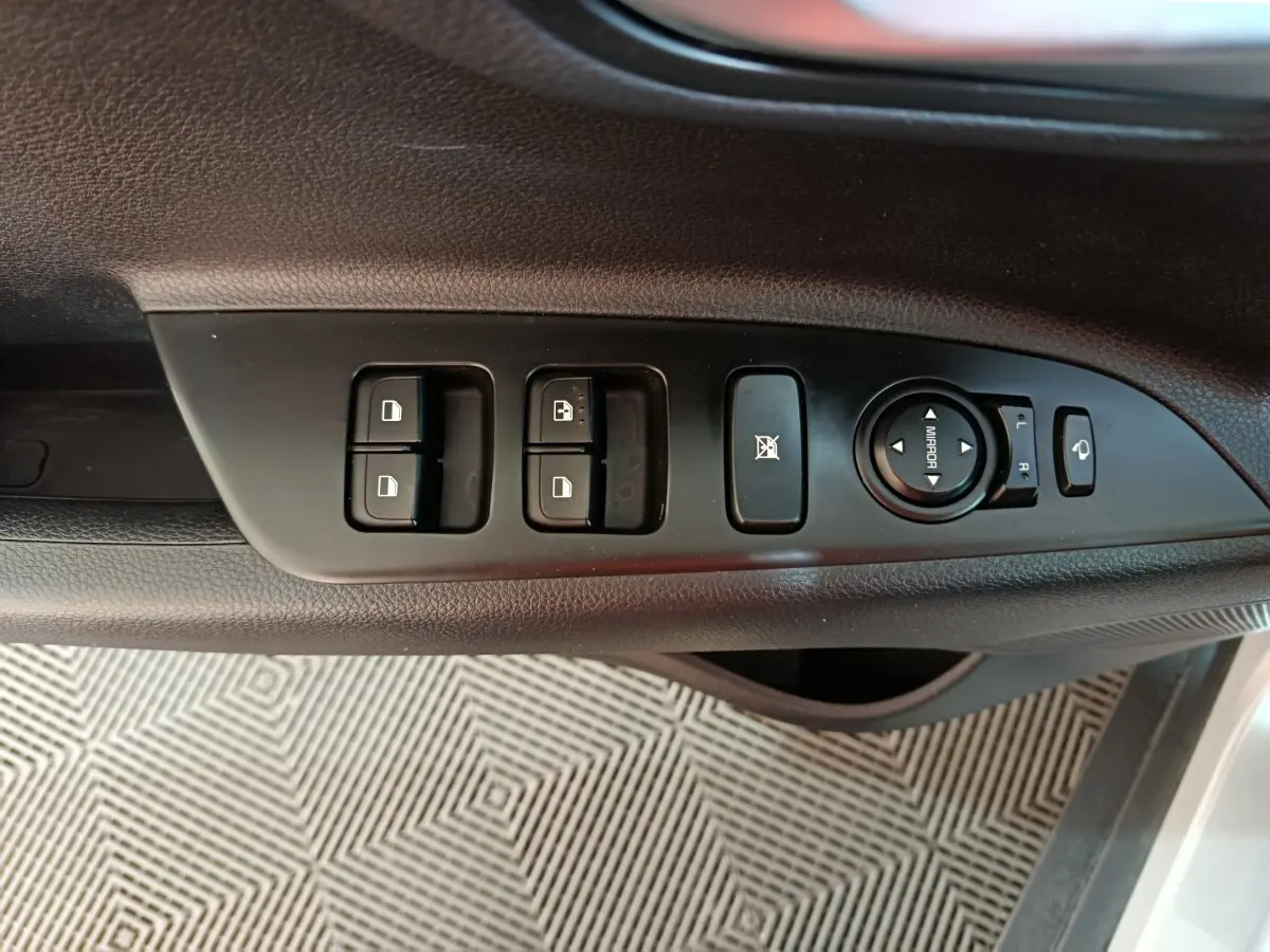 Vue rapprochée des commandes de porte côté gauche du KIA Stonic gris clair, avec réglage des rétroviseurs et boutons de verrouillage.