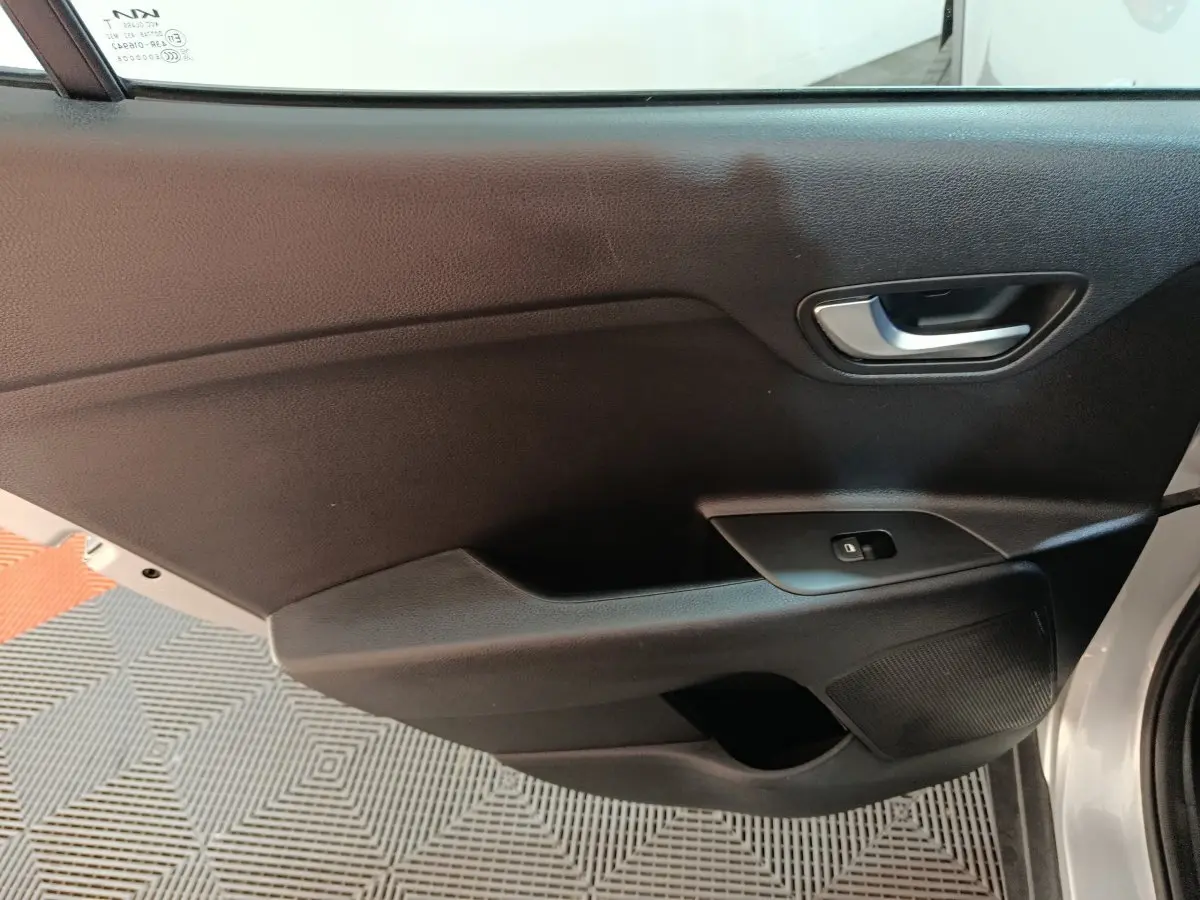 Vue rapprochée de la porte avant droite grise du KIA STONIC 1.0 T-GDI 100 URBAN avec poignée et commande de fenêtre.