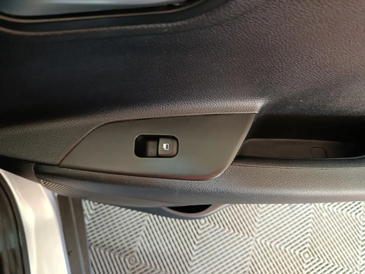 Gros plan sur le bouton de verrouillage de porte côté gauche de la portière intérieure d'une KIA Stonic gris clair 2022.