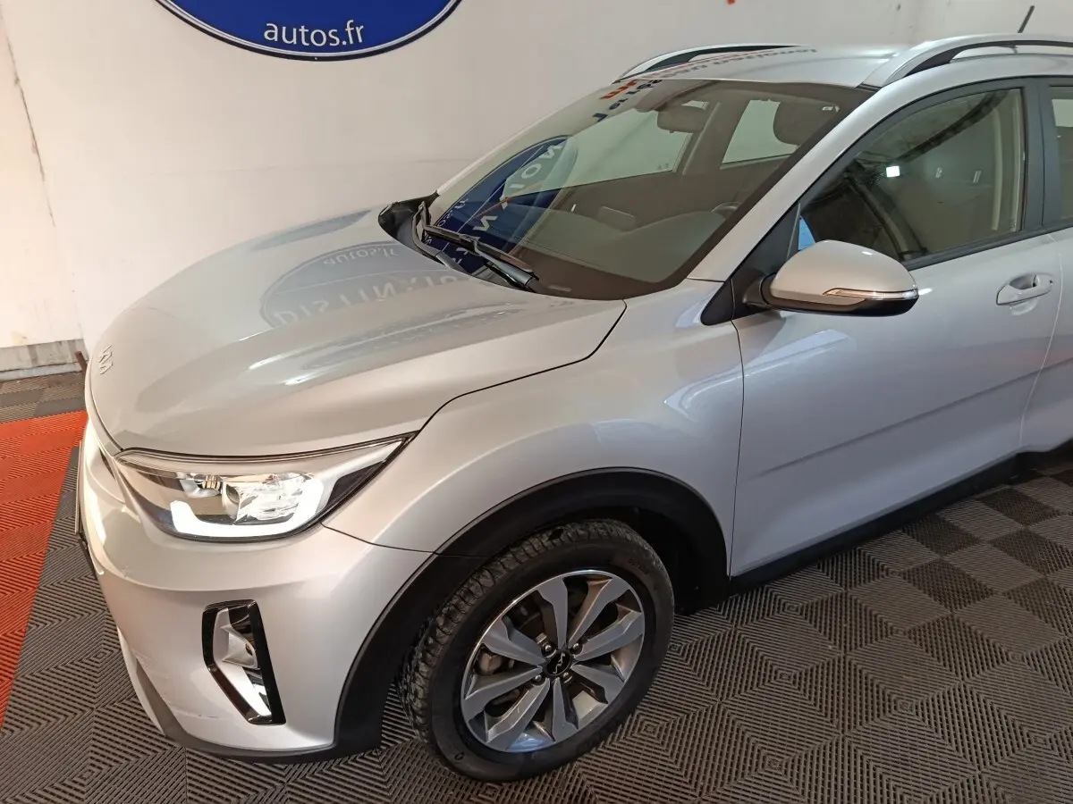 Vue 3/4 avant droit d'un KIA STONIC gris clair 2022 avec phares LED et jantes alliage distinctives.