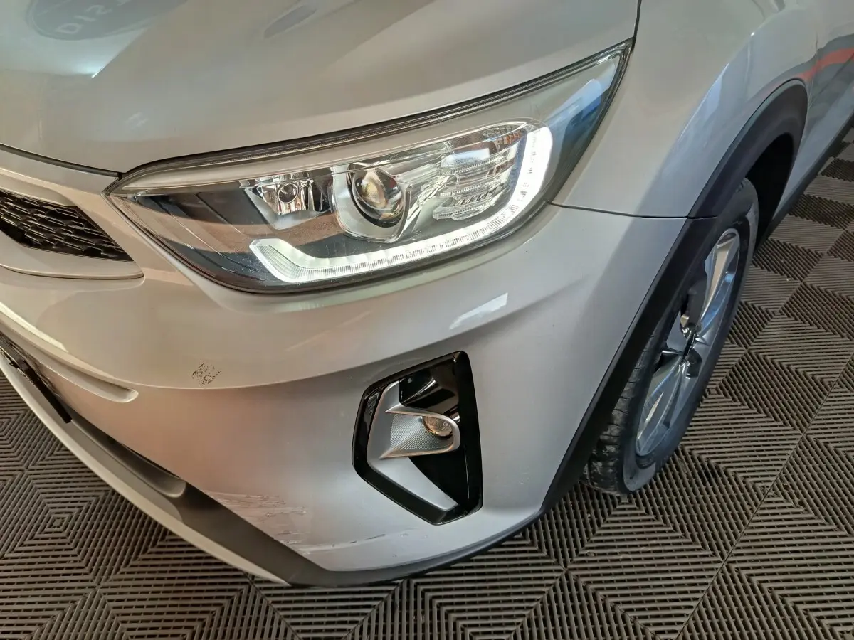 Vue rapprochée du coin avant droit d’un KIA Stonic gris clair 2022, mettant en valeur le phare LED et le antibrouillard.