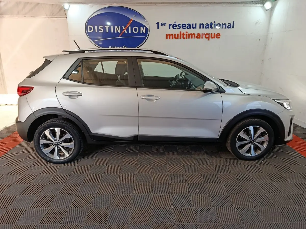 Profil droit d'un KIA STONIC gris clair 2022 en intérieur, avec jantes alliage et détails noirs sur les passages de roues.