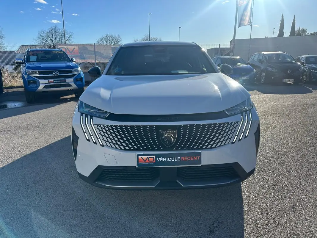 Vue avant d'un Peugeot 3008 Hybrid blanc de 2025 avec calandre distinctive et feux LED verticaux allumés.