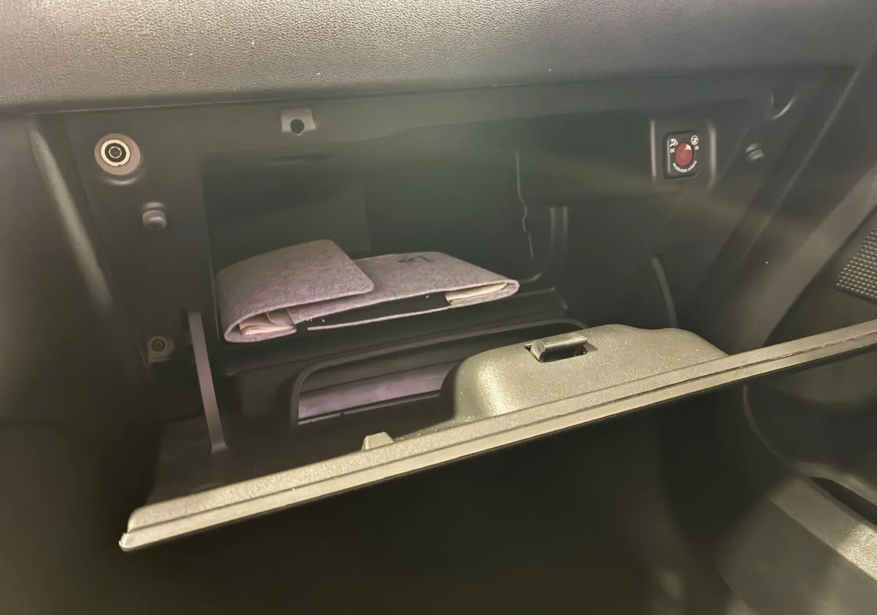 Gros plan sur la boîte à gants ouverte du Citroën C3 Aircross 2023 avec un carnet gris à l'intérieur.