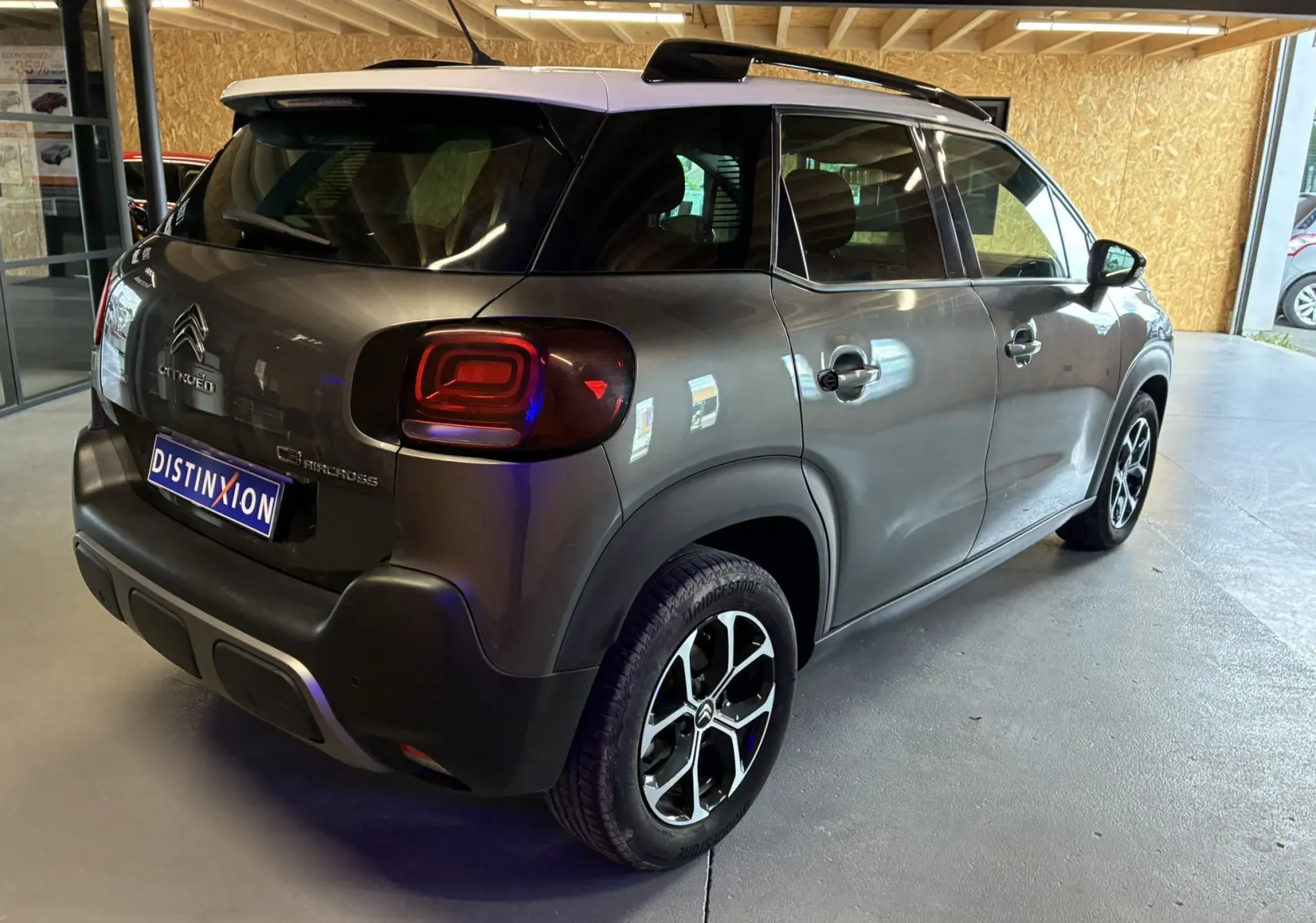 Vue 3/4 arrière droit d'une Citroën C3 Aircross gris platinium métal avec toit blanc et jantes alu bi-ton.
