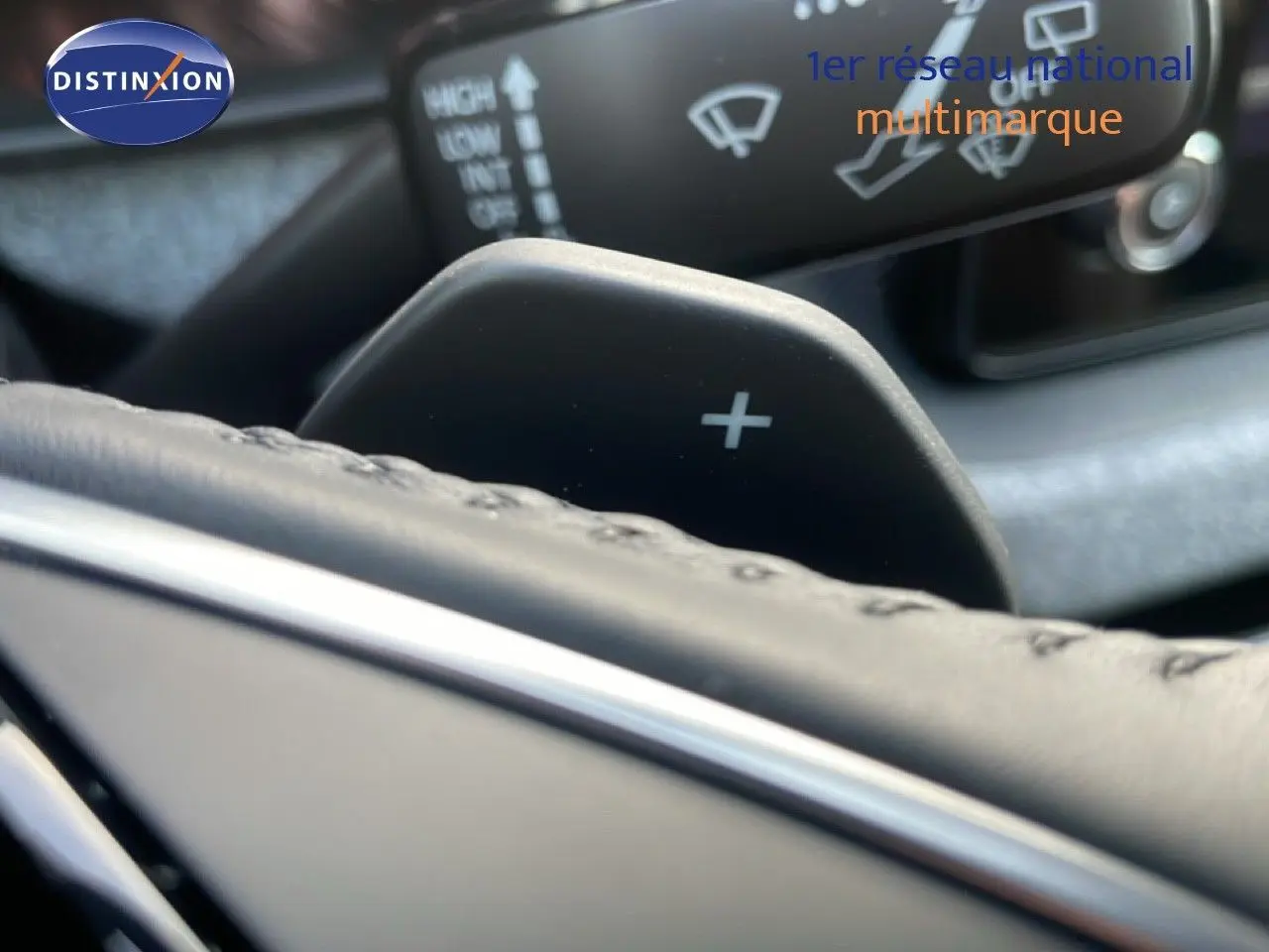 Gros plan sur la palette de changement de vitesse droite et partie du volant en cuir noir d'un Skoda Kamiq gris argent.