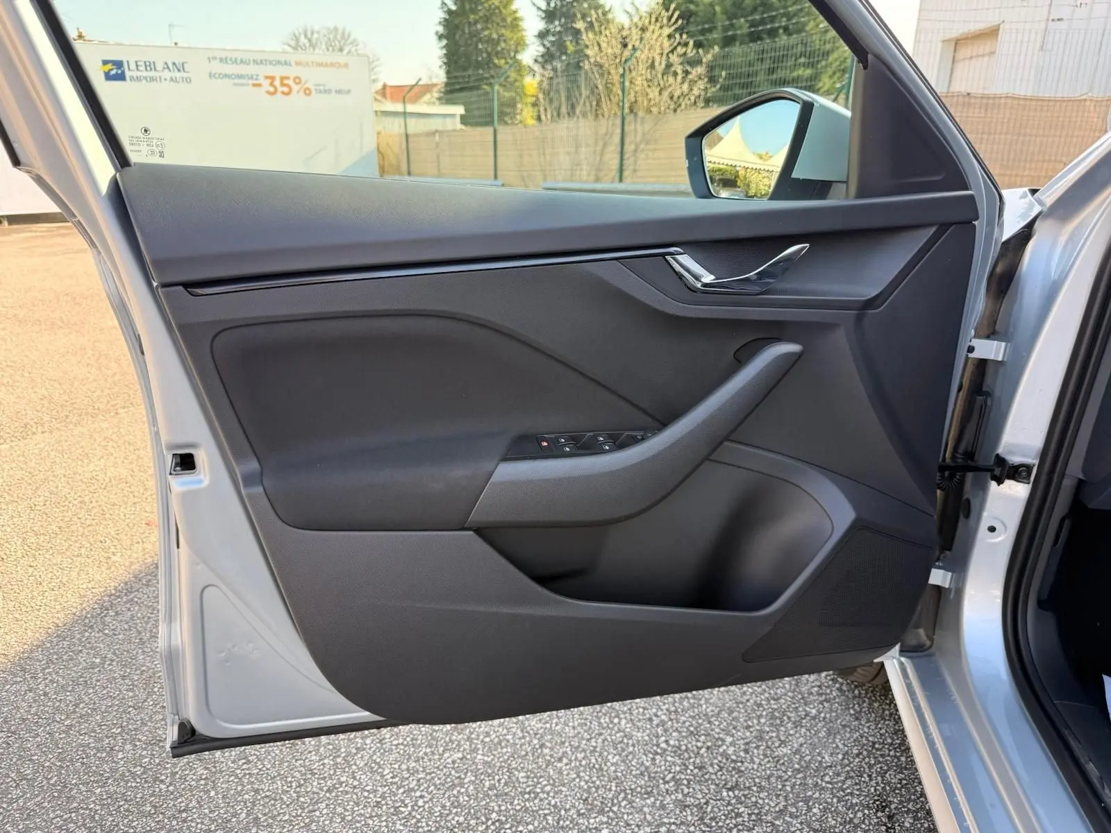 Vue rapprochée de la porte avant gauche gris argent métal d’un Skoda Kamiq 2025, avec commandes de vitres et poignée intégrée.
