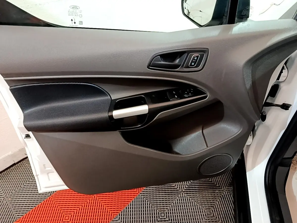 Vue rapprochée de la porte avant gauche blanche du Ford Transit Fourgon, avec commandes de vitres et poignée noire.