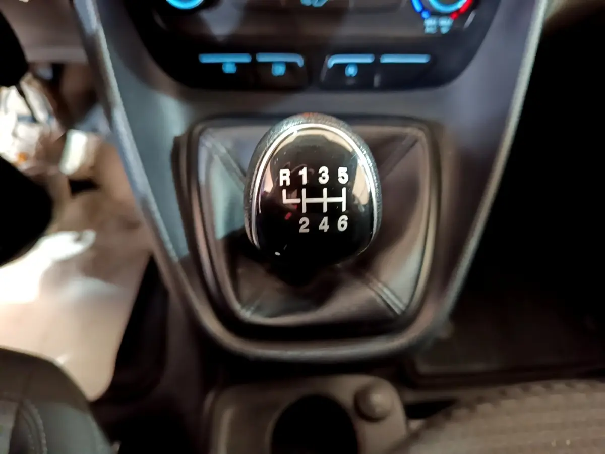 Gros plan sur le levier de vitesses manuel noir du Ford Transit Fourgon blanc, intérieur sombre.