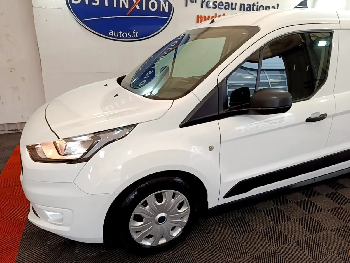 Vue 3/4 avant droit d’un Ford Transit Fourgon blanc avec phares allumés et jantes acier.