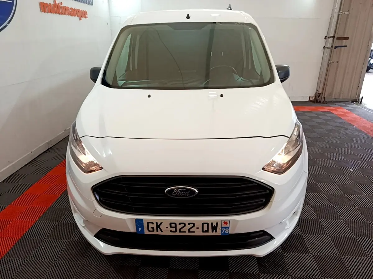 Vue avant d'un Ford Transit Fourgon blanc 2022 avec calandre noire et phares allumés en intérieur.