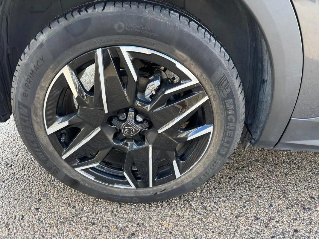 Gros plan sur la jante alliage noire et argent de 19 pouces du Peugeot 3008 Hybrid gris, avec pneu Michelin visible.