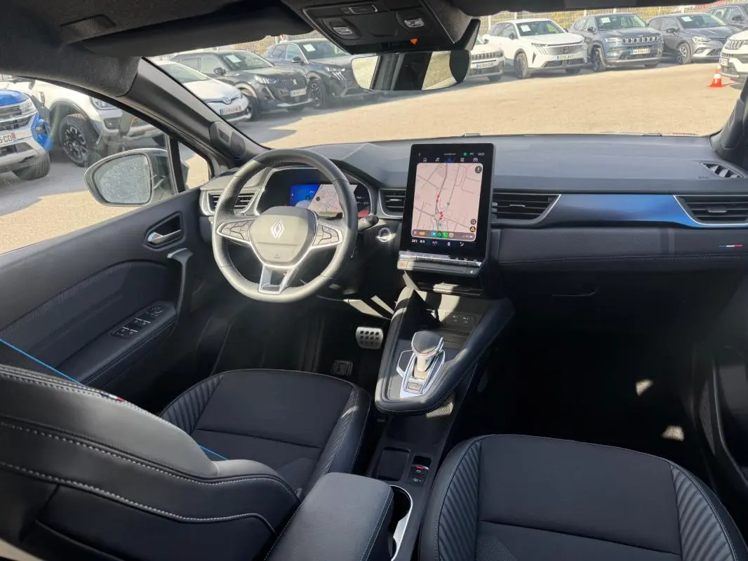 Vue intérieure avant gauche du Renault SYMBIOZ E-Tech gris clair, avec écran tactile vertical et volant multifonction.