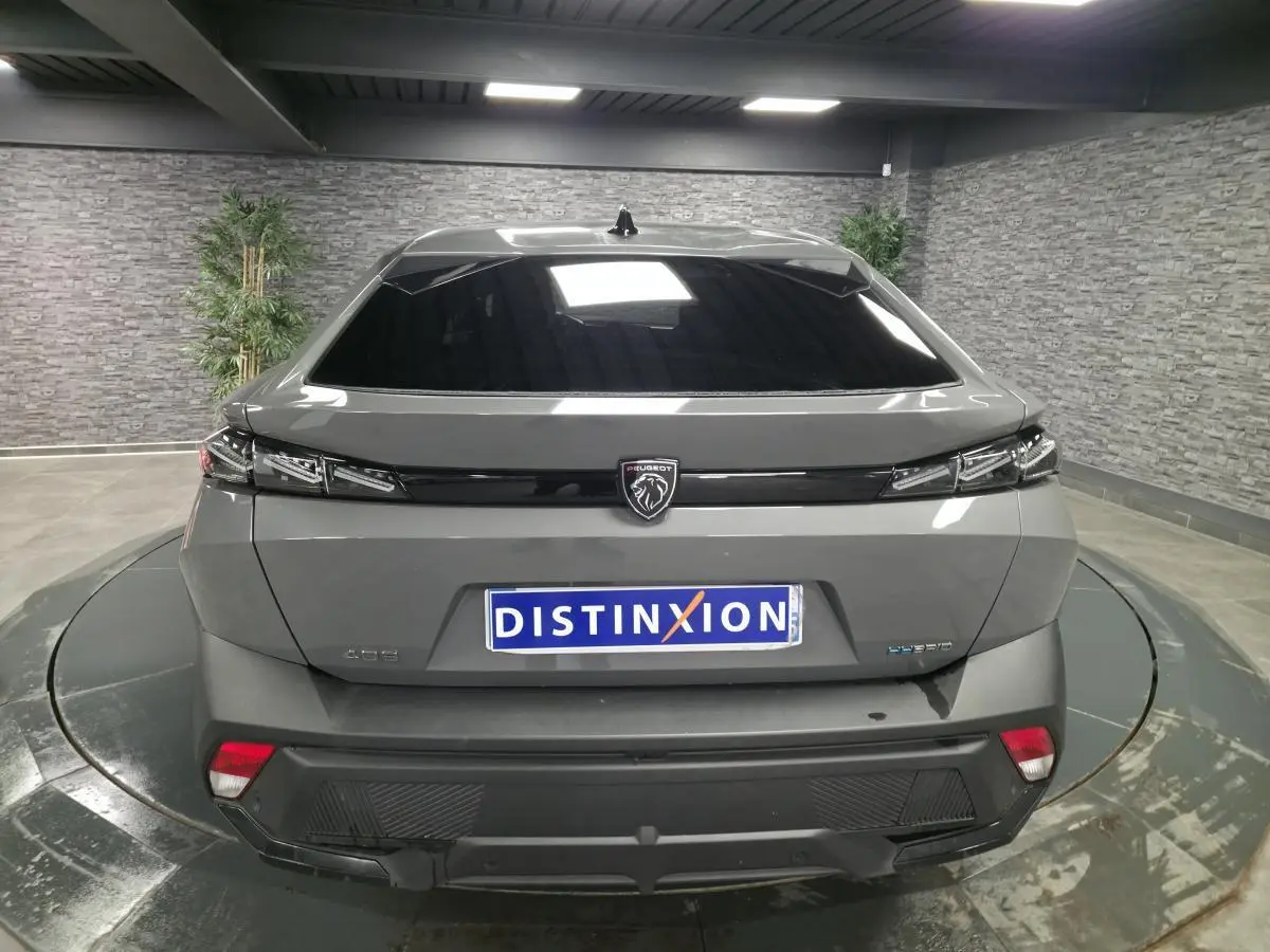 Vue arrière d'une Peugeot 408 gris métallisé avec feux arrière à LED et logo lion central noir brillant.