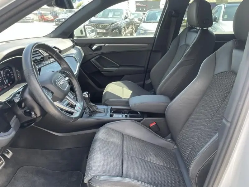 Vue intérieure côté conducteur de l'Audi Q3 blanc 35 TFSI S-Line 2021 avec sièges sport en cuir et console centrale moderne.