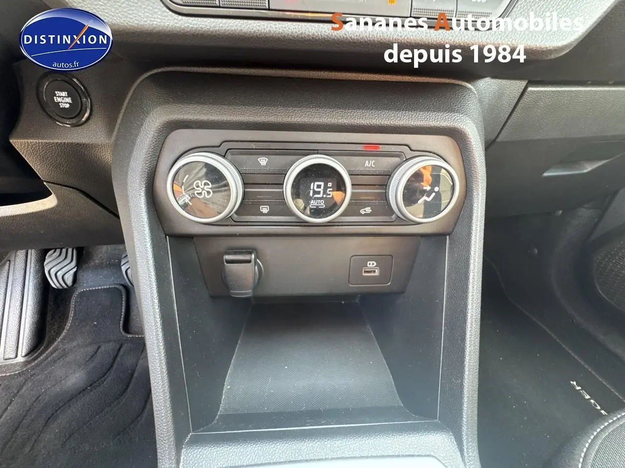 Vue rapprochée de la console centrale noire du Dacia Jogger 2023, avec commandes de climatisation et prise USB visible.