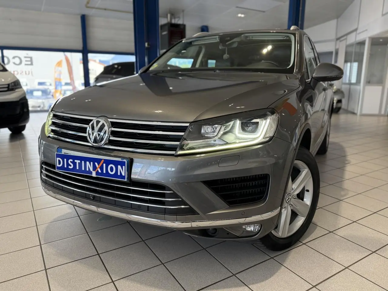Volkswagen Touareg gris foncé vu de 3/4 avant droit avec phares LED allumés en showroom.