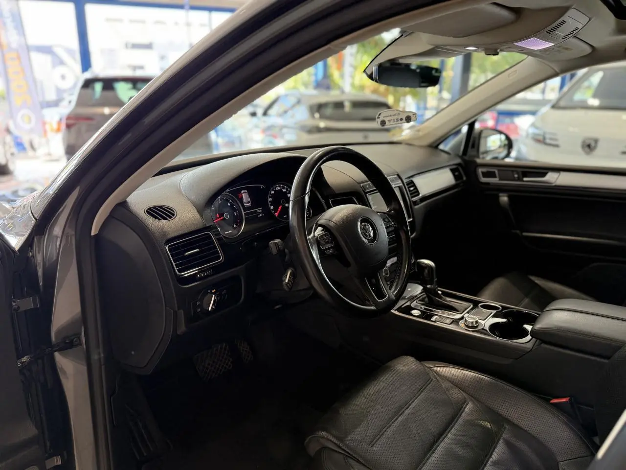 Intérieur noir cuir du Volkswagen Touareg 2017, vue côté conducteur avec tableau de bord et volant visibles.