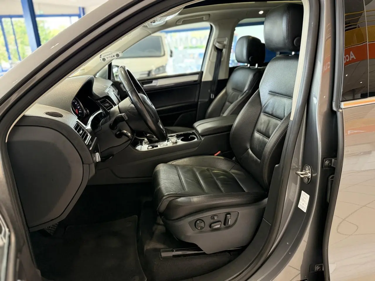 Intérieur côté conducteur du Volkswagen Touareg gris foncé 2017 avec sièges cuir noirs et console centrale visible.