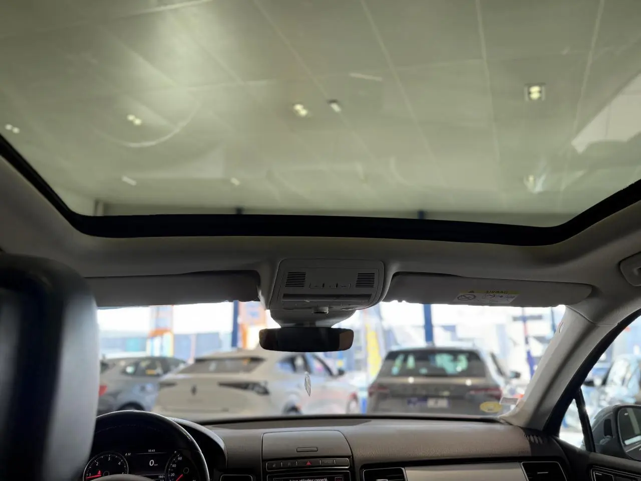 Vue intérieure avant du Volkswagen Touareg gris foncé 2017 avec toit ouvrant panoramique et tableau de bord épuré.