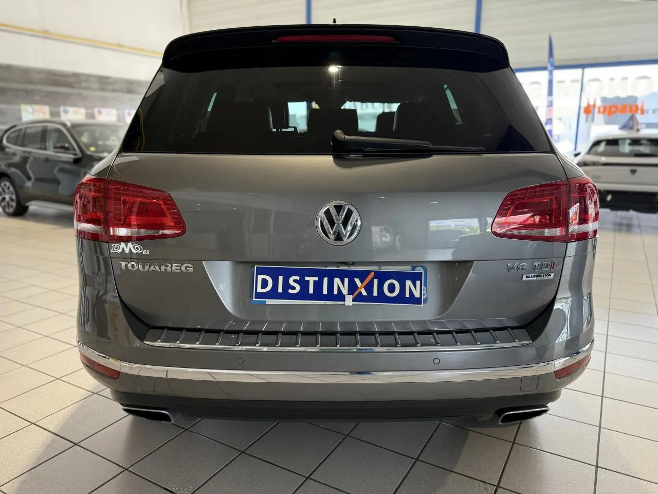Vue arrière d'un Volkswagen Touareg gris foncé avec plaques Distinxion et badges V6 TDI BlueMotion visibles.