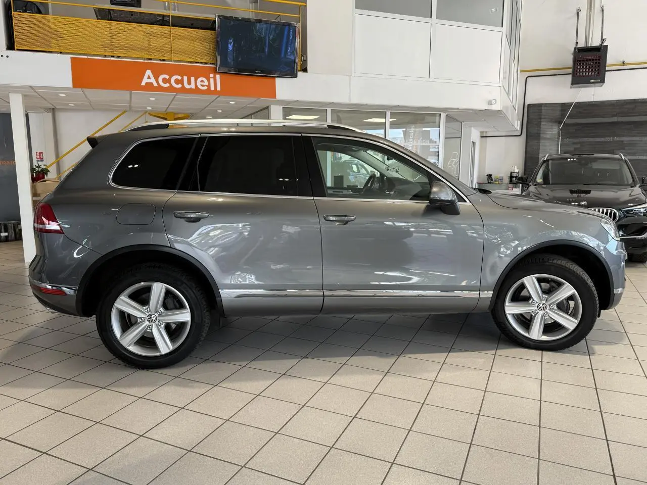 Profil côté droit d'un Volkswagen Touareg gris foncé 2017 en showroom, avec jantes alliage 19 pouces et vitres teintées.