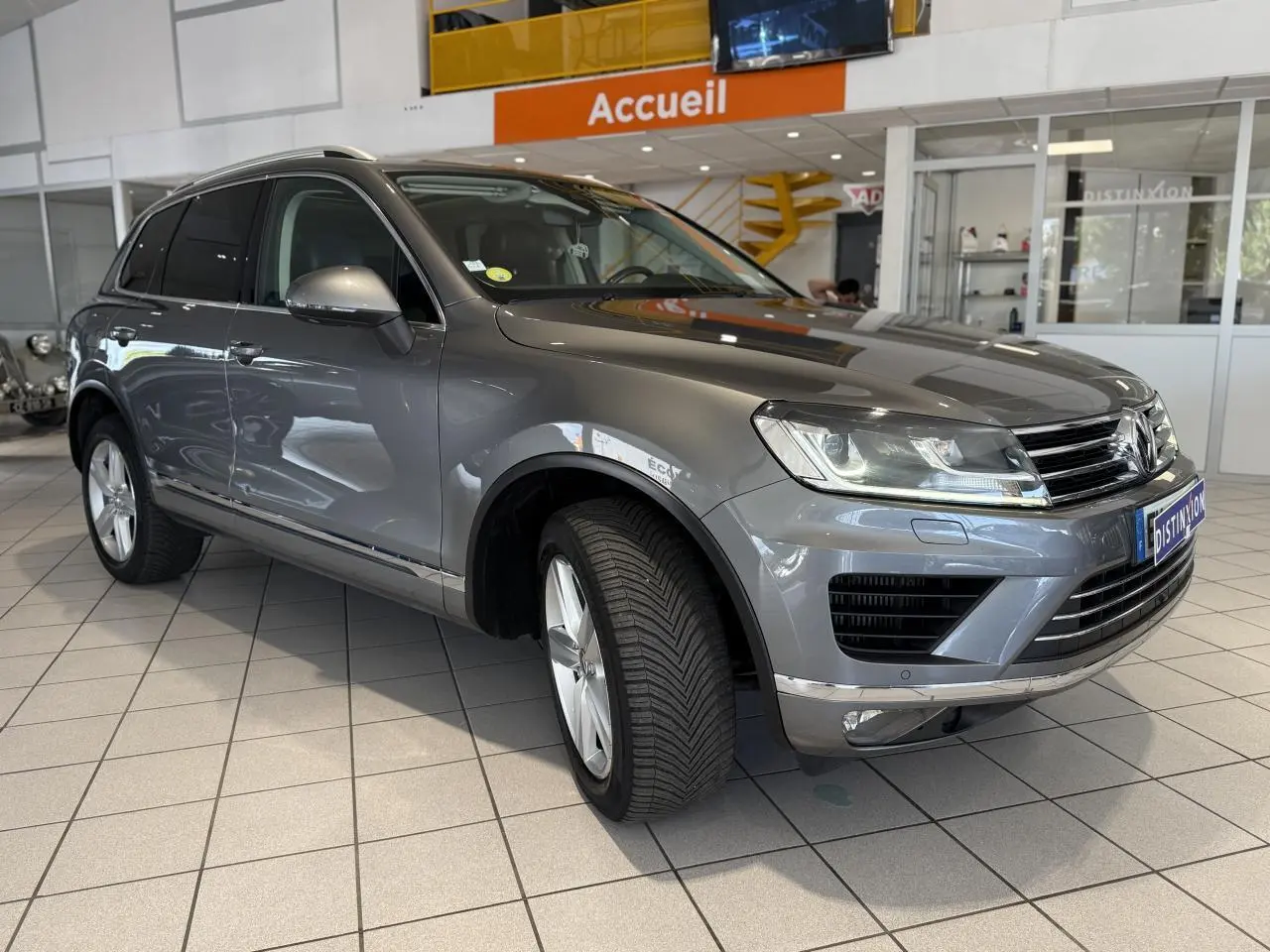 Volkswagen Touareg gris foncé vu en 3/4 avant droit dans un showroom avec éclairage intérieur.