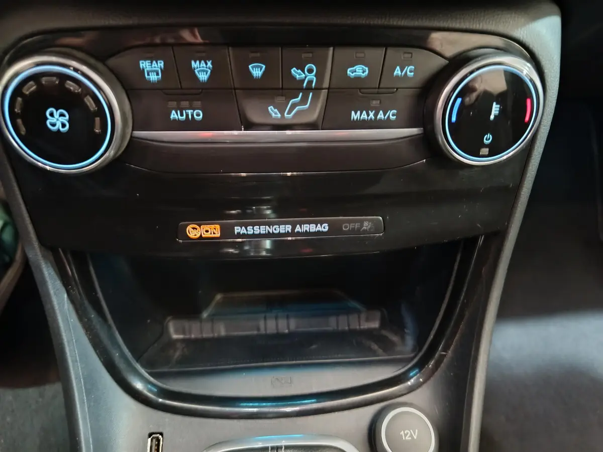 Détail du tableau de bord central noir avec commandes climatisation et témoin airbag passager du Ford Puma blanc 2022.