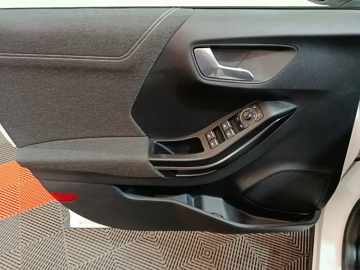 Vue rapprochée de la porte avant gauche blanche du Ford Puma 2022, montrant les commandes de vitres et la poignée intérieure.