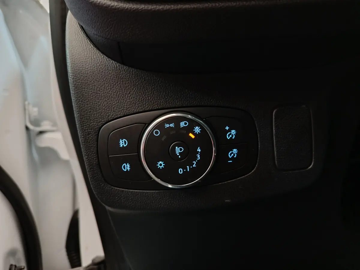 Gros plan sur le bouton de réglage des phares à LED du Ford Puma blanc, côté gauche intérieur conducteur.
