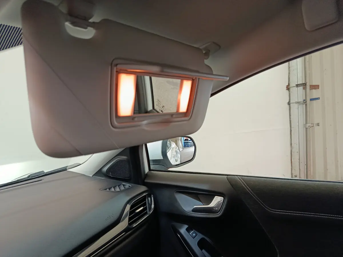 Intérieur côté conducteur du Ford Puma blanc 2022, avec miroir de soleil éclairé et tableau de bord visible.
