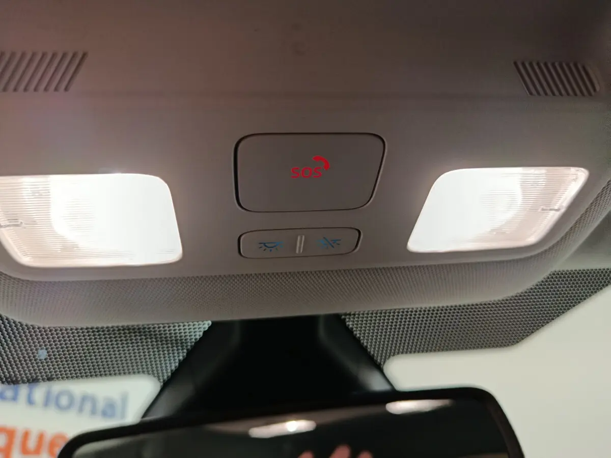 Vue intérieure du plafonnier avec bouton SOS rouge et éclairages de lecture allumés dans une Ford Puma blanche.