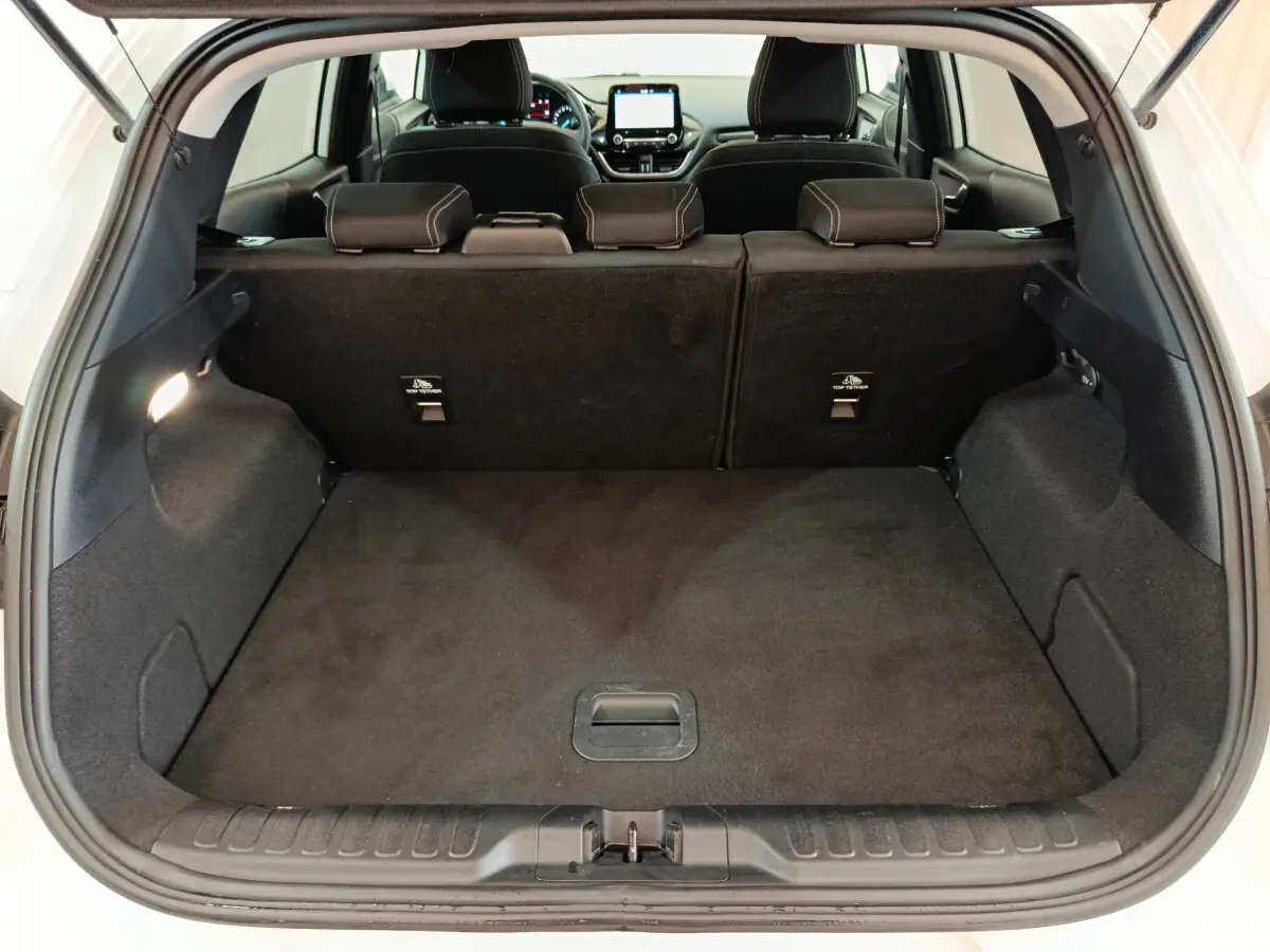 Coffre ouvert vu de l'arrière d'un Ford Puma blanc, montrant l'espace de chargement avec banquette arrière noire.