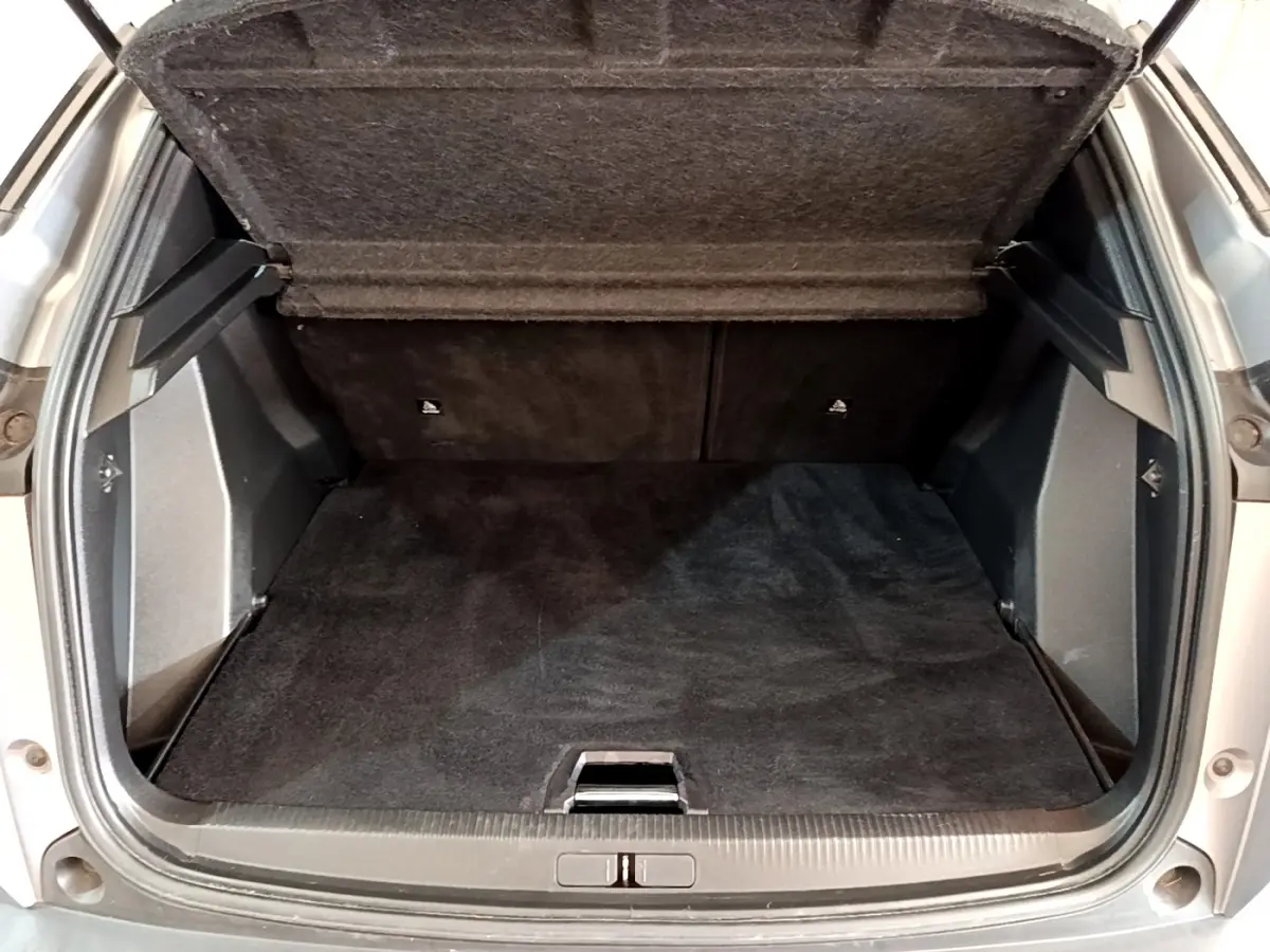 Coffre ouvert vu de l'arrière d'un Peugeot 2008 gris clair, montrant le plancher plat et la banquette rabattable.