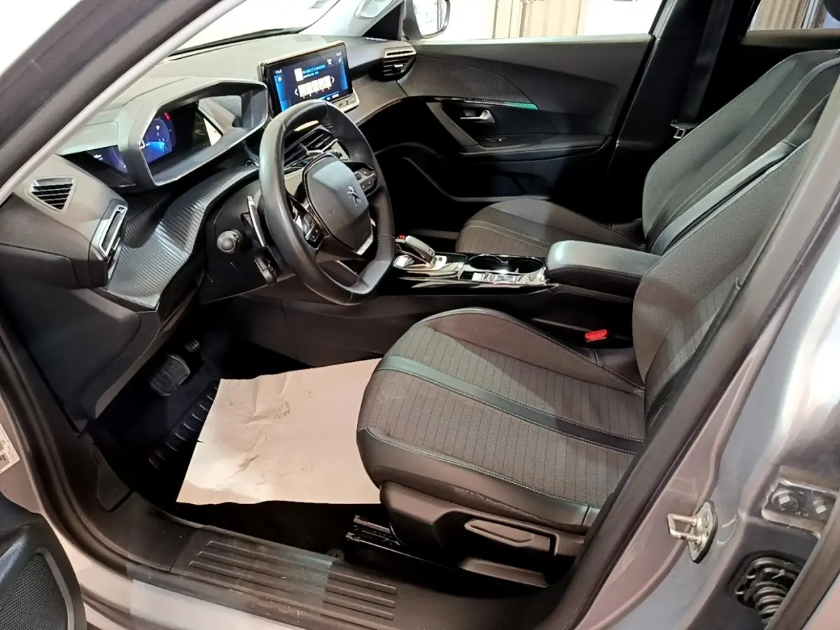 Intérieur côté conducteur du Peugeot 2008 gris clair 2021, avec tableau de bord numérique et volant cuir multifonctions.